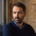 Portrait d'un homme barbu regardant pensivement par la fenêtre.